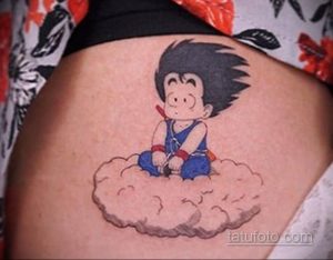 Цветное фото татуировки с изображением маленького Гоку из аниме Dragon Ball, сидящего на облаке. Татуировка выполнена на бедре.
