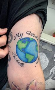 Фото татуировки на руке с изображением земного шара, окруженного надписью 'My World Isobelle Alba'. Используются яркие цвета и каллиграфический шрифт.