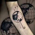 Фото тату: татуировка с изображением глобуса Земли, окруженного линиями долготы и широты на руке. Черно-белое исполнение, детализированная проработка.