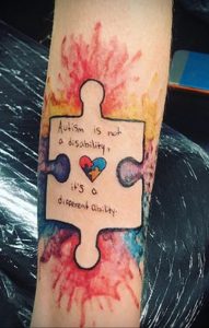 Фото тату на руке: элемент пазла с надписью 'Autism is not a disability, it's a different ability' и сердцем внутри. Символ поддержки людей с аутизмом.