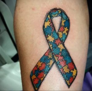 Фото тату на руке: лента, состоящая из разноцветных элементов пазла. Символизирует поддержку людей с аутизмом и осведомленность об этом расстройстве.