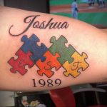 Фото тату на предплечье: разноцветные пазлы, имя 'Joshua' и дата '1989'. Символизирует важные моменты жизни и индивидуальность.