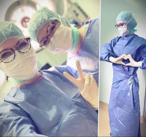 Фотография двух медицинских работниц в шапочках и масках, одна из которых показывает знак мира. На заднем плане - еще одна медицинская работница.