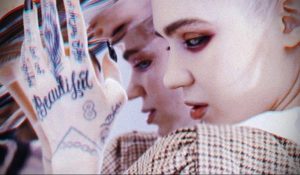 Фото тату: крупный план рук Grimes с татуировками, включая надпись 'Beautiful' и другие символы. Детализированный рисунок татуировки.