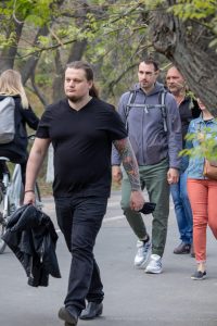 Фотография мужчины с яркой татуировкой на руке, изображающей тигра и цветы. Виден детализированный рисунок в ярких цветах.