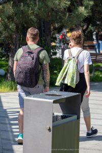 Фотография мужчины с татуировкой на руке и женщины с рюкзаком, идущих по улице. Видна часть татуировки в стиле традиционной графики.