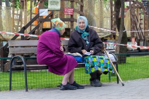 Фотография двух женщин, сидящих на скамейке в парке, одна из которых имеет татуировку на руке.
