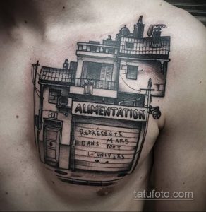 Фото тату здания с надписями на груди. Черно-белый рисунок в стиле графики с детальной проработкой архитектурных элементов.