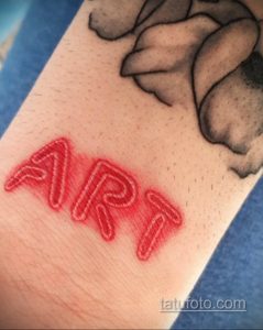Фото татуировки с надписью "ART", выполненной в стиле неоновой вывески, с красными контурами и светящимся эффектом.