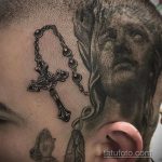 Фото татуировки на голове с изображением креста, чет и молящихся рук. Рисунок выполнен в реалистичном стиле, с использованием черно-белой гаммы. Религиозная и символичная татуировка.