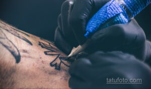 Фото процесса татуировки: рука мастера с тату-машинкой наносит рисунок на кожу. Идеально для тех, кто интересуется процессом создания татуировок.