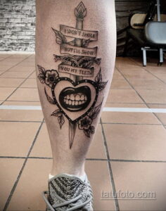 Фото тату с надписью "I won't smile but I'll show you my teeth" и изображением сердца, пронзенного стрелой. Стиль old school.