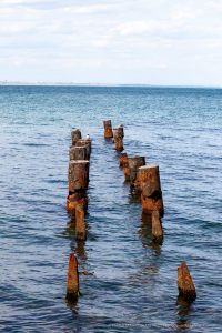 Фото тату: Старые деревянные сваи в море, на фоне голубого неба и воды.
