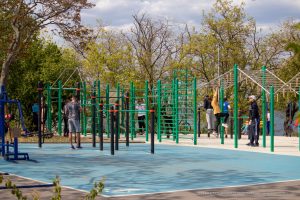 Фото тату: Группа людей занимается спортом на уличной площадке, у некоторых видны татуировки на руках и ногах.
