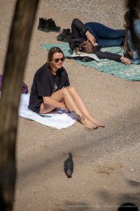 Фото тату на лодыжке женщины: небольшая татуировка, частично видимая на ноге, на фоне пляжного отдыха. Идеально для демонстрации тату в повседневной жизни.