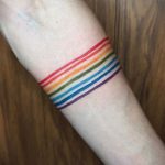 Фото тату: минималистичная радуга в виде нескольких цветных линий на запястье. Яркие цвета, простой дизайн, идея для татуировки.