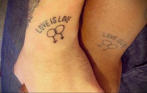 Фото тату: парные татуировки "Love is Love" с символами мужского и женского пола на запястьях.