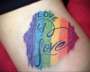 Фото тату: радужный фон с надписью "Love is Love". Яркий и позитивный рисунок татуировки.