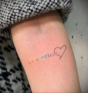 Фото минималистичной татуировки на руке с надписью 'Love myself' и изображением сердца. Мотивирующая фраза, простой дизайн.