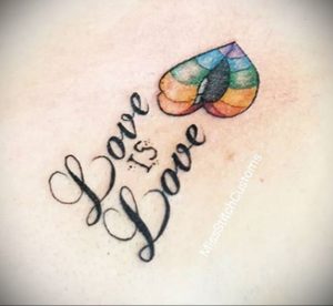 Фото татуировки с надписью "Love is Love" и изображением сердца, окрашенного в цвета радуги. Символичный и вдохновляющий рисунок.