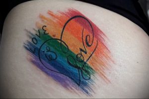 Фото тату сердца, окрашенного в цвета радуги, с надписью 'LOVE IS LOVE'. Яркий и позитивный рисунок татуировки, символизирующий любовь и принятие.