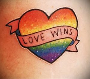 Фото тату сердца, окрашенного в цвета радуги, с надписью 'LOVE WINS'. Яркий и позитивный рисунок татуировки, символизирующий любовь и принятие.