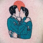 Татуировка в стиле олдскул с изображением двух мужчин, целующихся на фоне красного круга, символизирующая любовь и страсть.