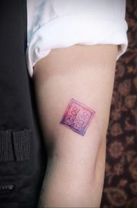 Фото тату с изображением корейских иероглифов на коже. Тату выполнено в нежных розовых и фиолетовых тонах.