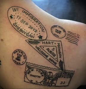Фото тату на спине: татуировка, состоящая из нескольких почтовых штемпелей с датами и названиями городов, а также изображения флага, символизирующая путешествия и иммиграцию.
