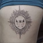 Фото тату: татуировка солнца и луны с двумя лицами внутри на бедре. Мистический и загадочный рисунок.