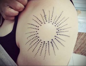 Фото тату: оригинальная татуировка солнца, выполненная точками (dotwork) на плече. Необычный и стильный рисунок.