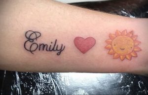 Фото татуировки на предплечье с надписью 'Emily', сердцем и изображением мультяшного Солнца в ярких цветах.