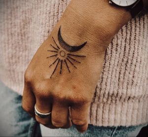 Фото тату на руке: солнце и луна в стиле dotwork, черные точки, минималистичный дизайн, нежный рисунок, женственная татуировка.