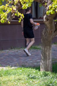 Фото тату на плече мужчины, идущего по улице. Видна часть татуировки в черных тонах, выполненной в графическом стиле.