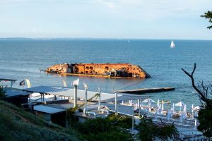 Фотография ржавого затонувшего корабля в море, спокойная вода, голубое небо. Отличный вариант для тату в морской тематике.