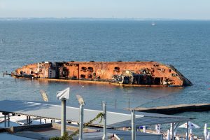 Фотография затонувшего корабля в море, ржавый корпус, голубая вода, солнечный день. Идеально для эскиза тату в морской тематике.