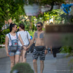 Фотография мужчины с татуировкой на торсе, идущего с женщиной по улице. Татуировка выполнена в реалистичном стиле и изображает тигра и цветы.