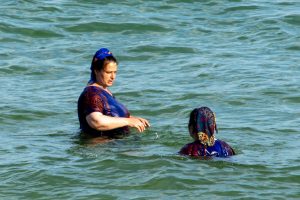 Фотография двух женщин, плавающих в море, одна смотрит в сторону, другая повернулась лицом к зрителю.