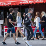 Фото тату на руке и плече мужчины, изображающее яркую и детализированную композицию с морскими элементами и цветами. Мужчина идет по улице.