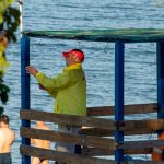 Фото спасателя на пляже в Одессе, стоящего на вышке с красным флагом и наблюдающего за морем.