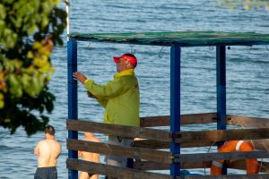Фото спасателя на пляже в Одессе, стоящего на вышке с красным флагом и наблюдающего за морем.