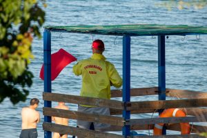 Фото спасателя на пляже в Одессе, стоящего на вышке с красным флагом и спасательным оборудованием.