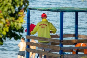 Фото спасателя на пляже в Одессе, стоящего на вышке с красным флагом и держащего в руках шест.