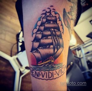 Фото тату: яркий рисунок парусника на фоне заката, с латинским девизом "Veni, Vidi, Vici", выполненный в стиле олд скул с четкими контурами и насыщенными цветами.