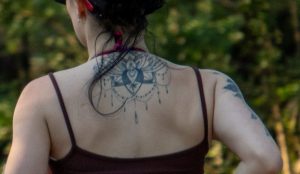 Фото тату на спине девушки: сложная мандала с множеством деталей и геометрических узоров. Черно-белый рисунок татуировки.