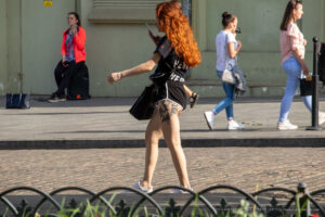 Фото тату реалистичной совы на бедре рыжеволосой девушки. Детализированный рисунок татуировки с использованием черных и серых оттенков.