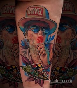 Красочная татуировка на руке с изображением девушки в очках, кепке Marvel и с леденцом во рту. Динамичный и запоминающийся рисунок в стиле комиксов.
