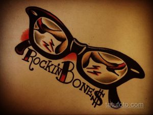 Фото тату на коже: черные очки с надписью 'Rockin' Bones' и символами молнии и доллара. Стиль олдскул с яркими красными акцентами.