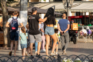 Фото тату: Женщина с татуировкой на ноге, идущая с семьей по улице. Идеи для тату на бедрах и голенях.