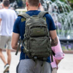 Фото тату: Черный ворон на руке мужчины, выполненный в графическом стиле с элементами брызг краски. Идеи для тату на предплечье.